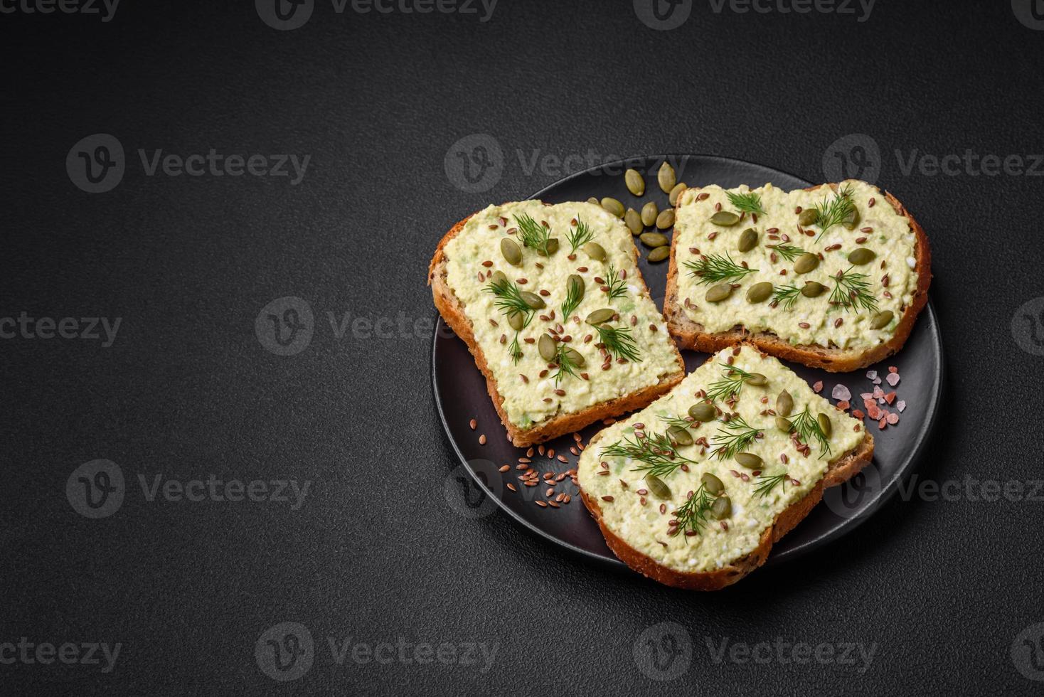 Grilled toast with avocado paste, eggs, cream cheese, salt, spices and herbs photo