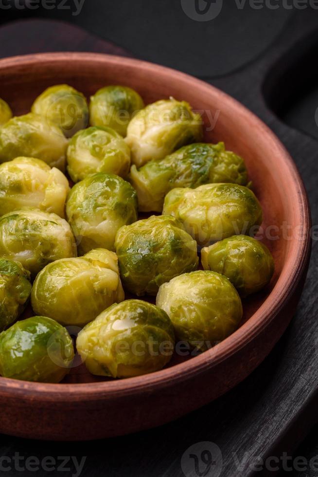 Delicious boiled Brussels sprouts on a ceramic plate on a dark concrete background photo