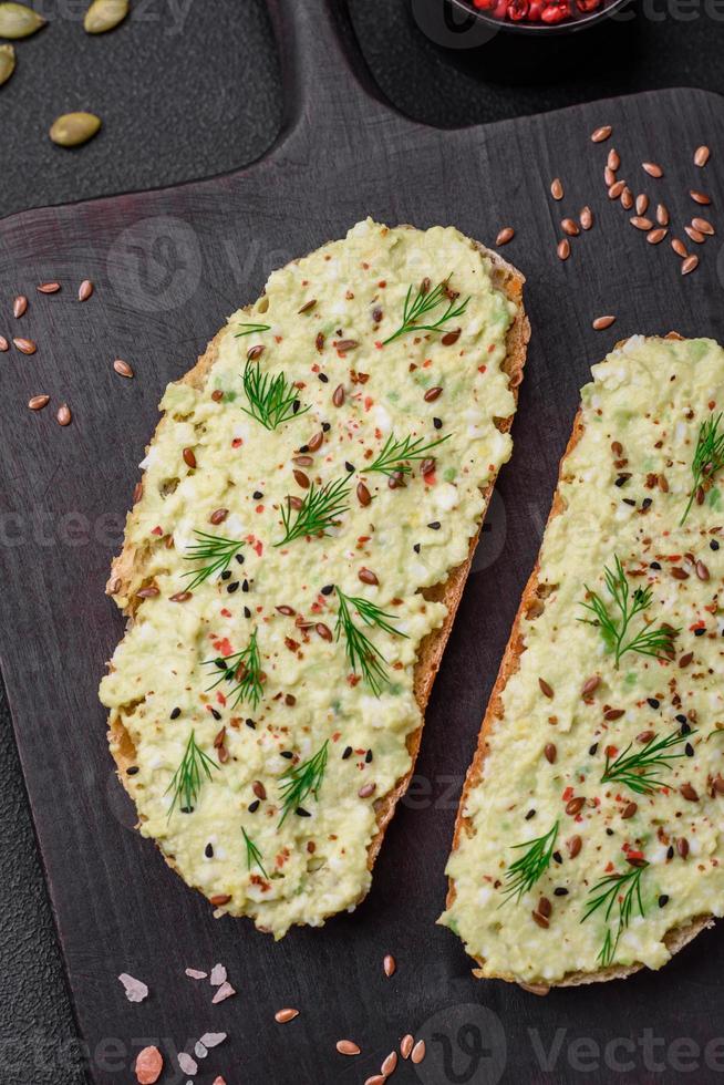 Grilled toast with avocado paste, eggs, cream cheese, salt, spices and herbs photo