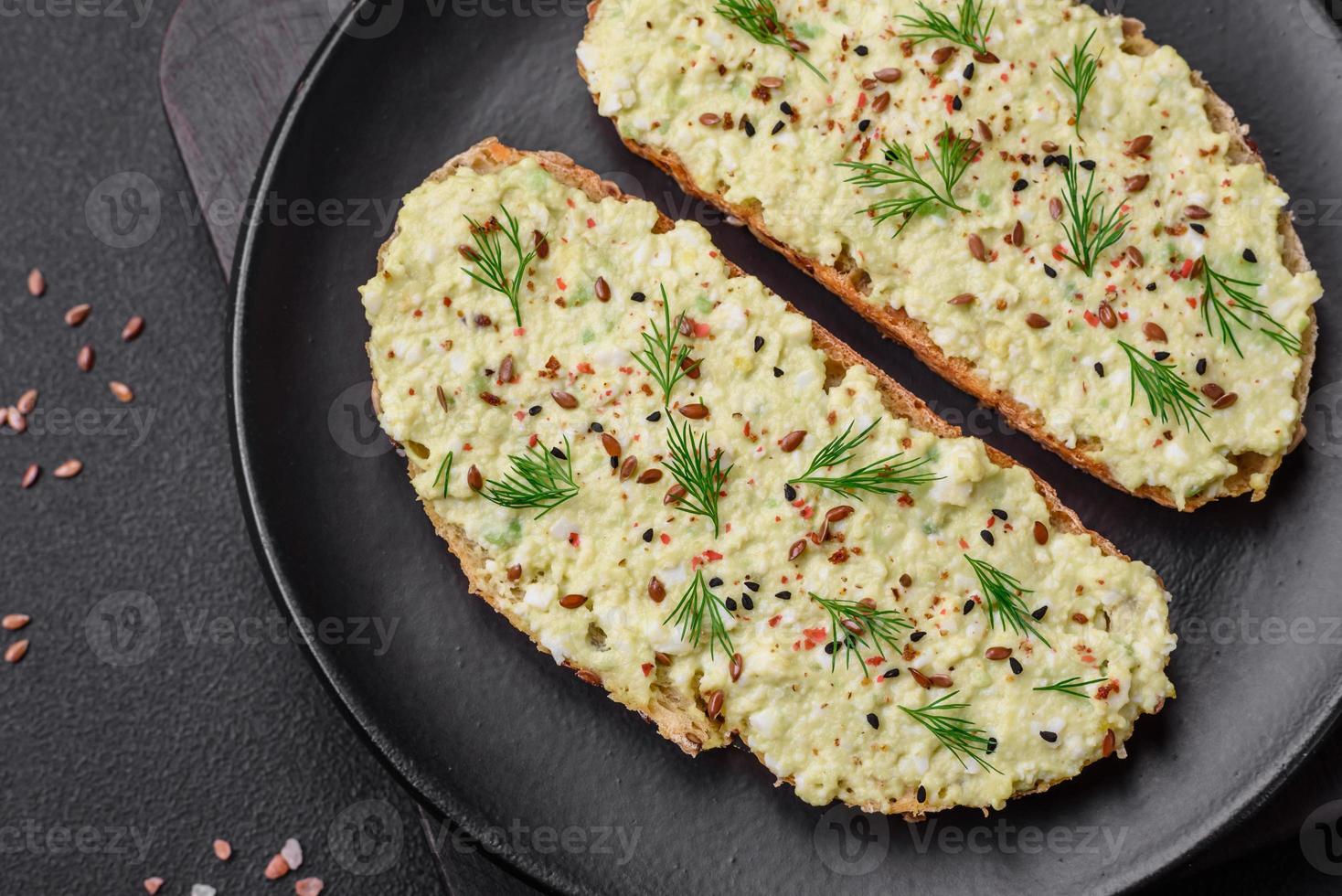 Grilled toast with avocado paste, eggs, cream cheese, salt, spices and herbs photo