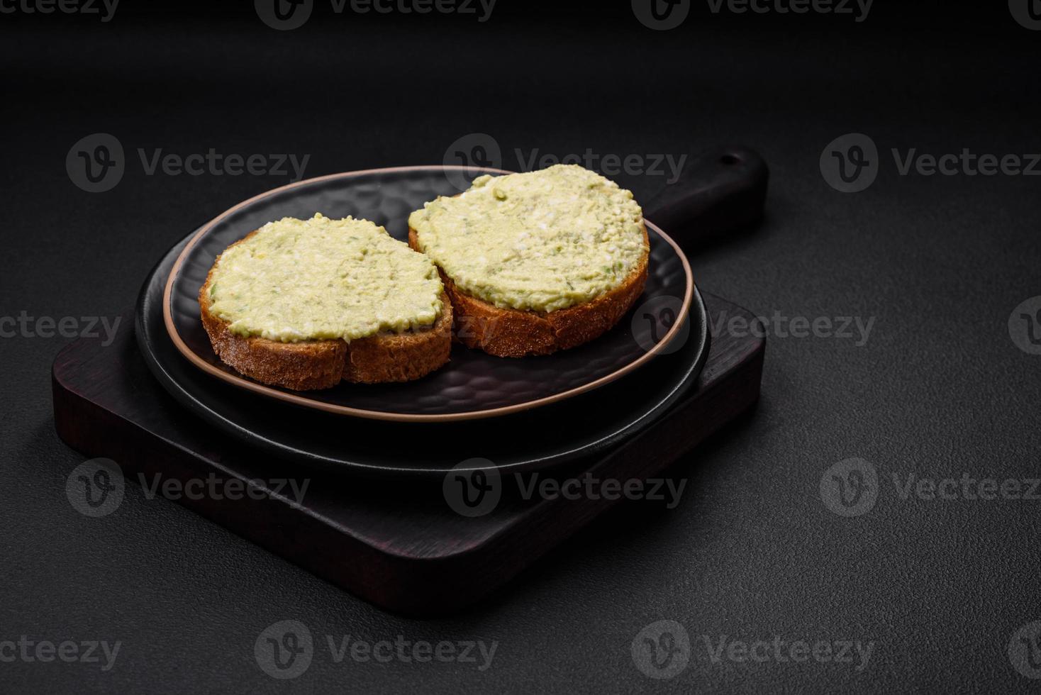 Grilled toast with avocado paste, eggs, cream cheese, salt, spices and herbs photo
