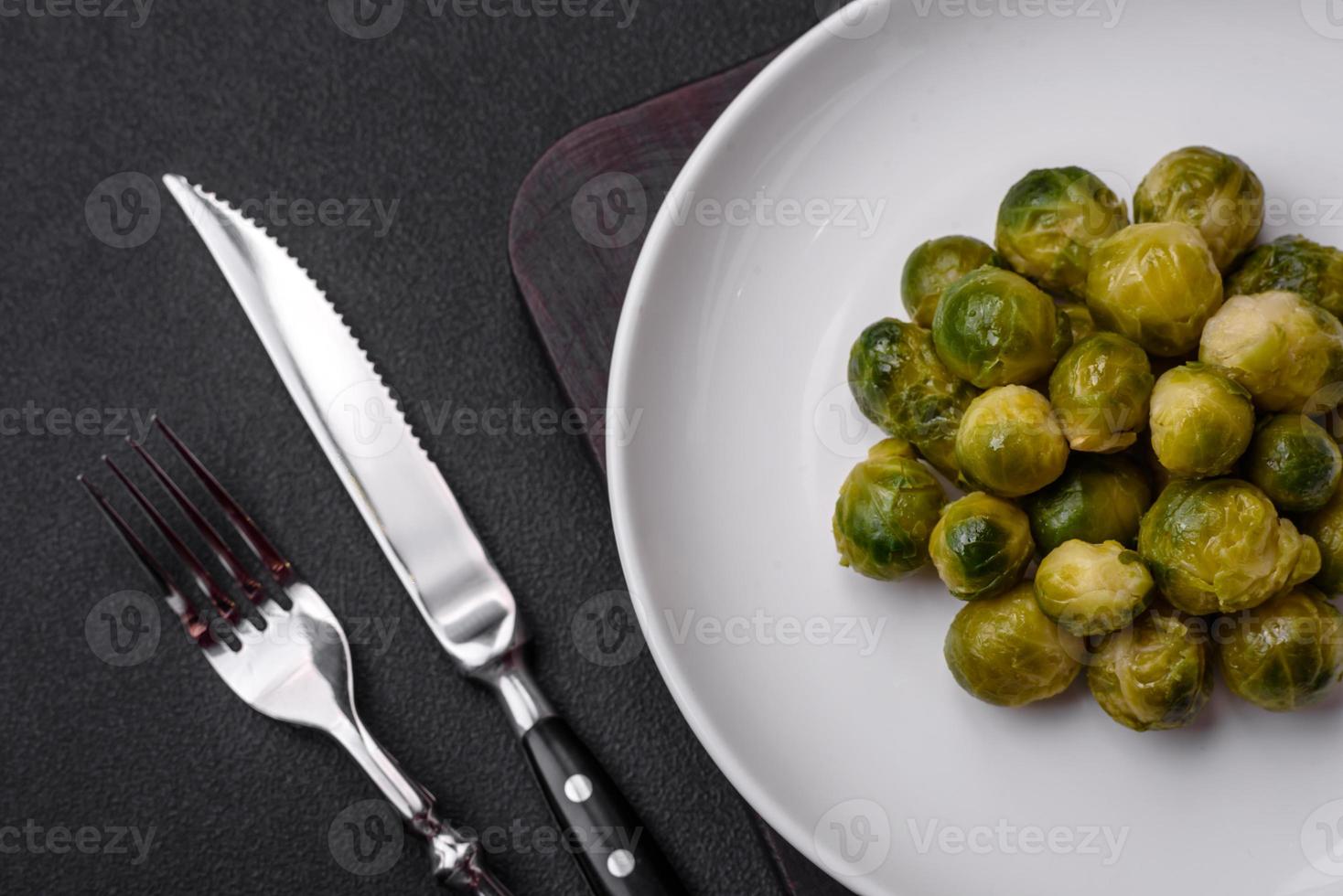 Delicious boiled Brussels sprouts on a ceramic plate on a dark concrete background photo