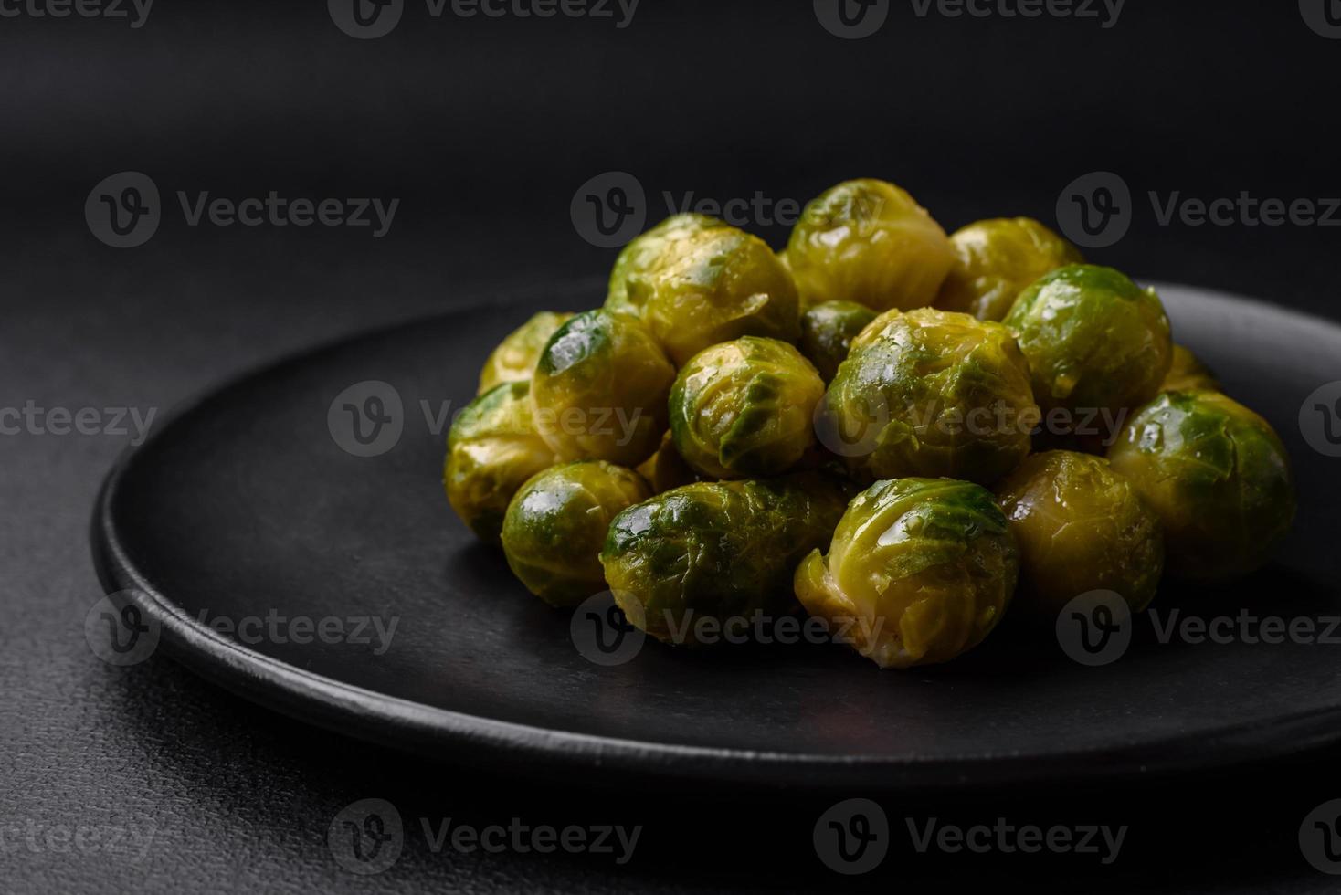 Delicious boiled Brussels sprouts on a ceramic plate on a dark concrete background photo