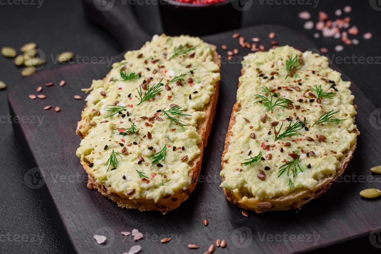 Grilled toast with avocado paste, eggs, cream cheese, salt, spices and herbs photo