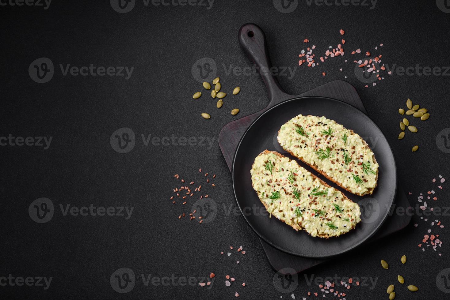 Grilled toast with avocado paste, eggs, cream cheese, salt, spices and herbs photo