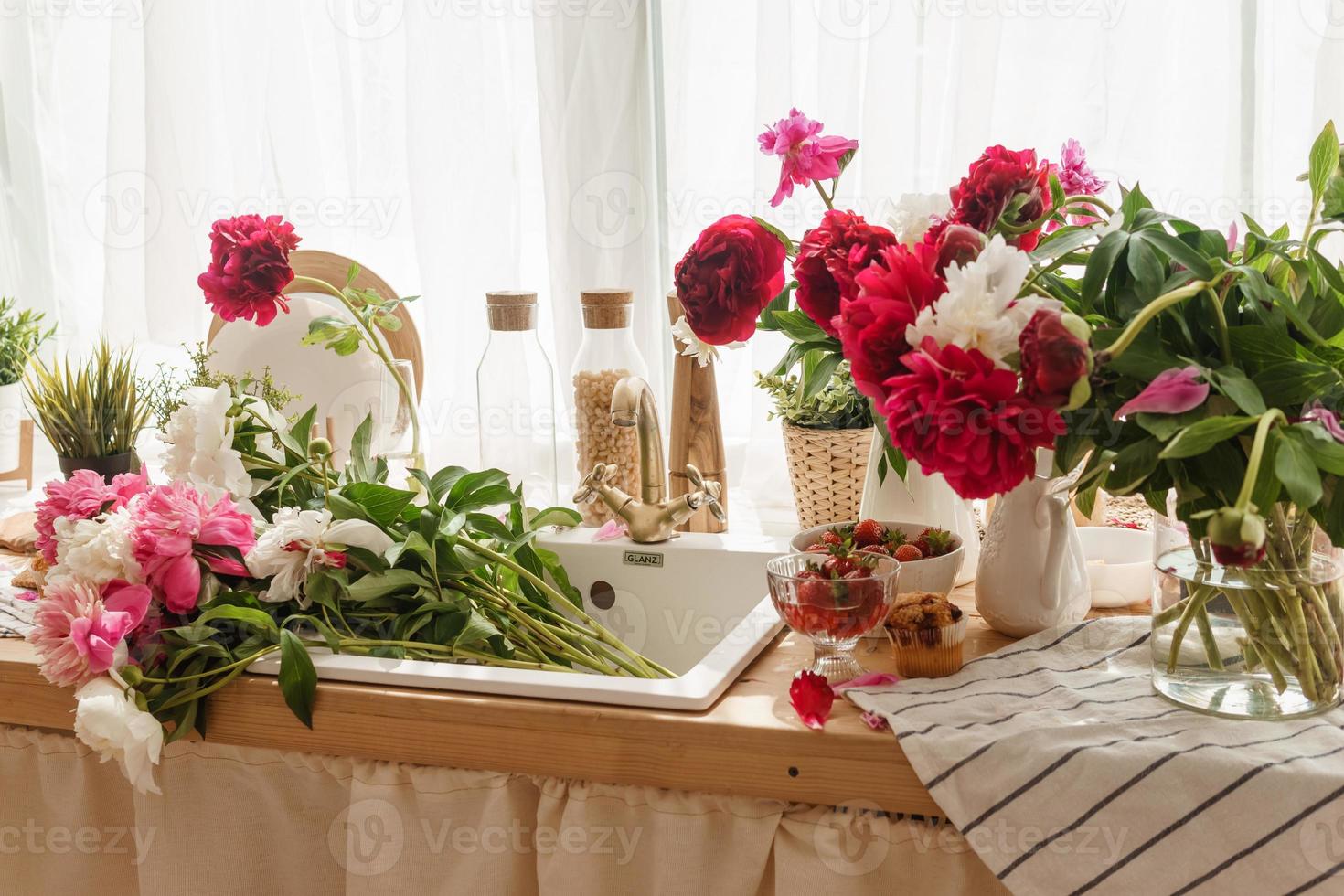 The kitchen countertop is decorated with peonies. The interior is decorated with spring flowers. photo