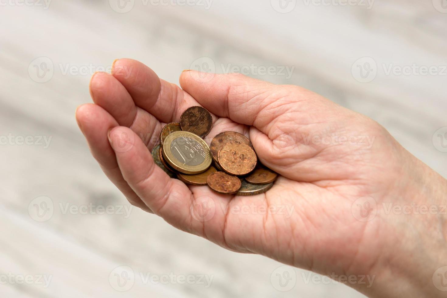 en el mano de un mayor persona, oxidado monedas y uno euro, social garantías, antiguo años foto