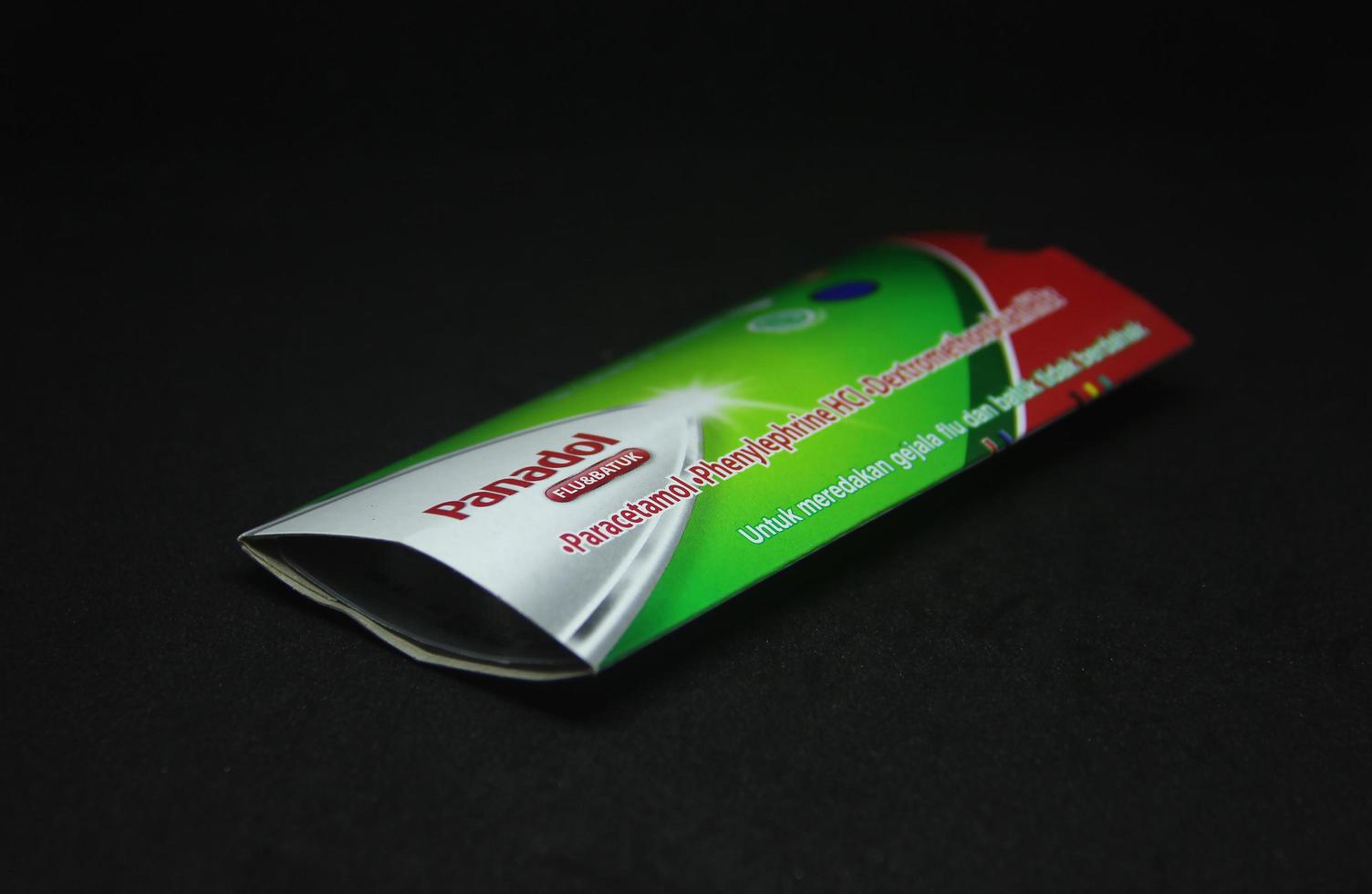Jakarta, Indonesia - April 21th, 2023 - Panadol tablet hijau. Fever, cough, and flu product object photography isolated on dark black background. Paracetamol medication. photo