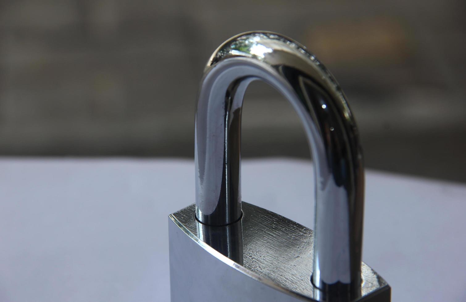Shiny new close up steel metal padlock isolated on white and brick flooring background. photo