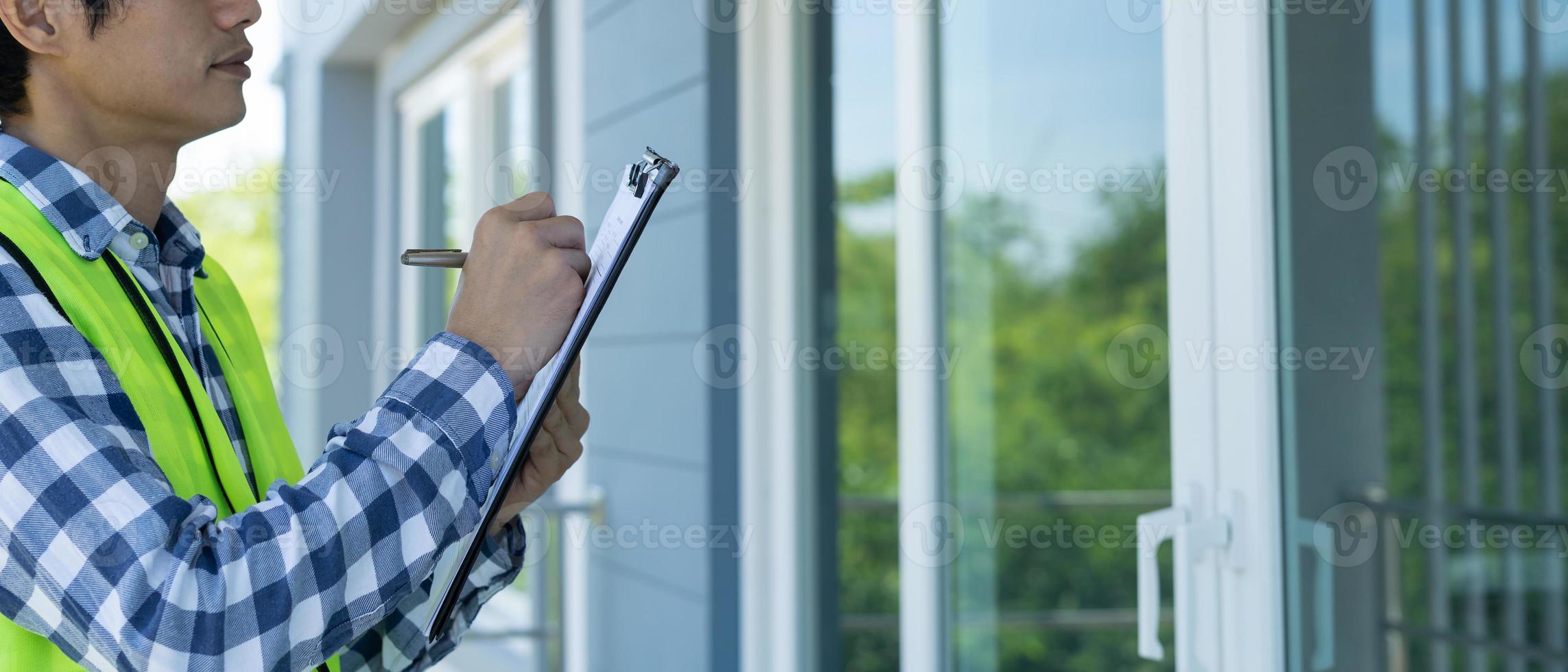 el inspector o ingeniero está inspeccionando la construcción y el aseguramiento de la calidad de la nueva casa usando una lista de verificación. ingenieros o arquitectos o contratistas trabajan para construir la casa antes de entregársela al propietario foto