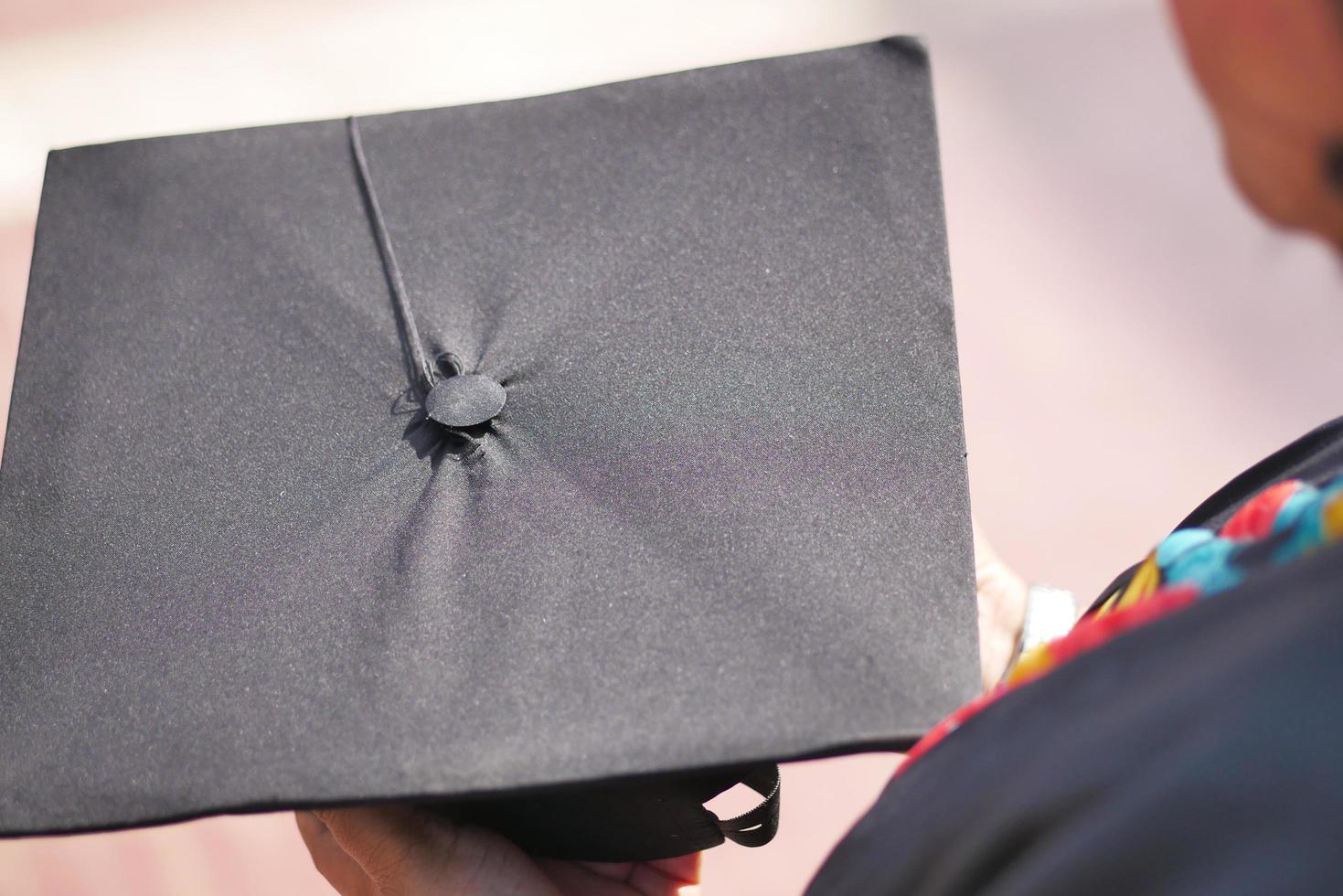 estudiante sostenga sombreros en la mano durante el éxito del comienzo con fondo amarillo foto