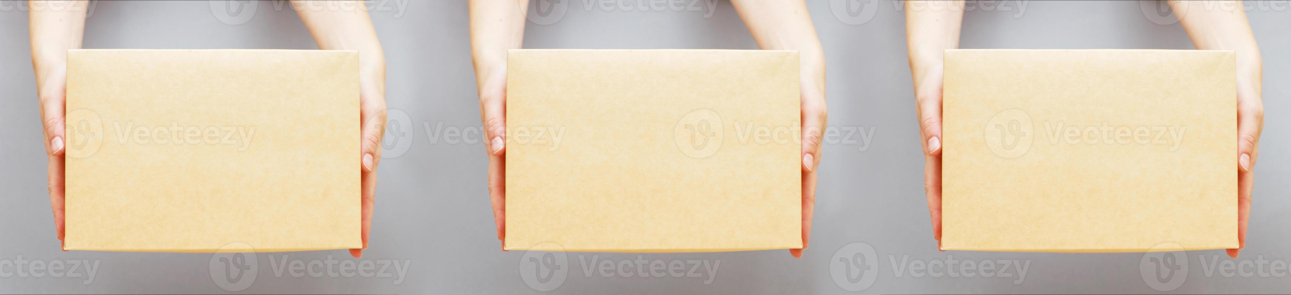 human hands holding delivers carton box on grey background. Delivery and online shopping concept. photo