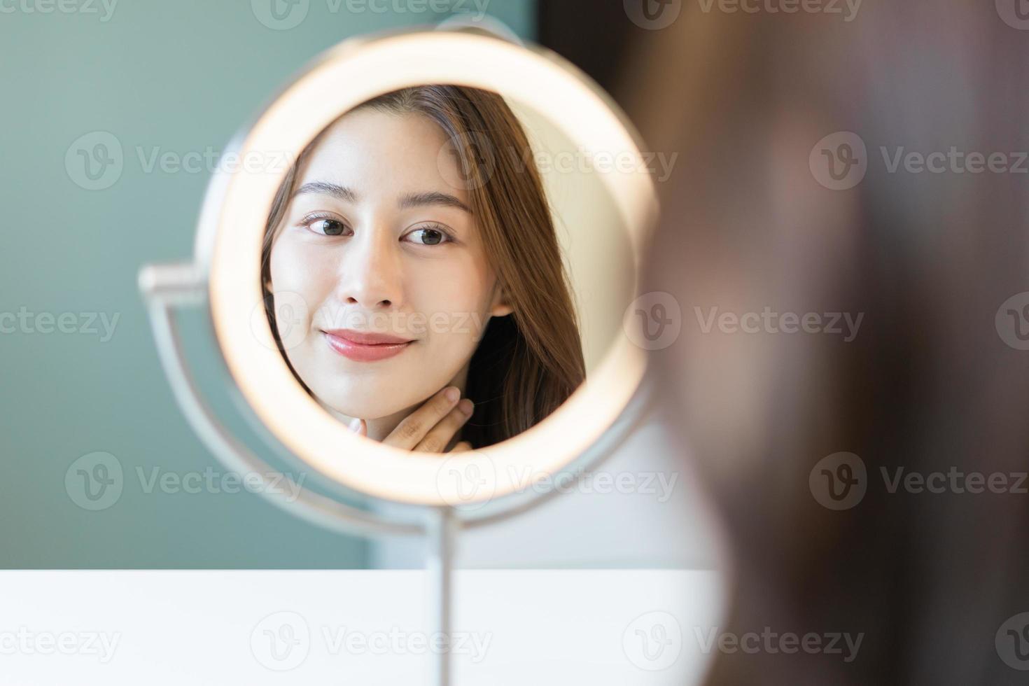Fresh, nice healthy skin, beautiful of asian young woman, girl looking at mirror, touching her face with before make up cosmetic routine at home. Female look with natural fashion style, Facial Beauty. photo