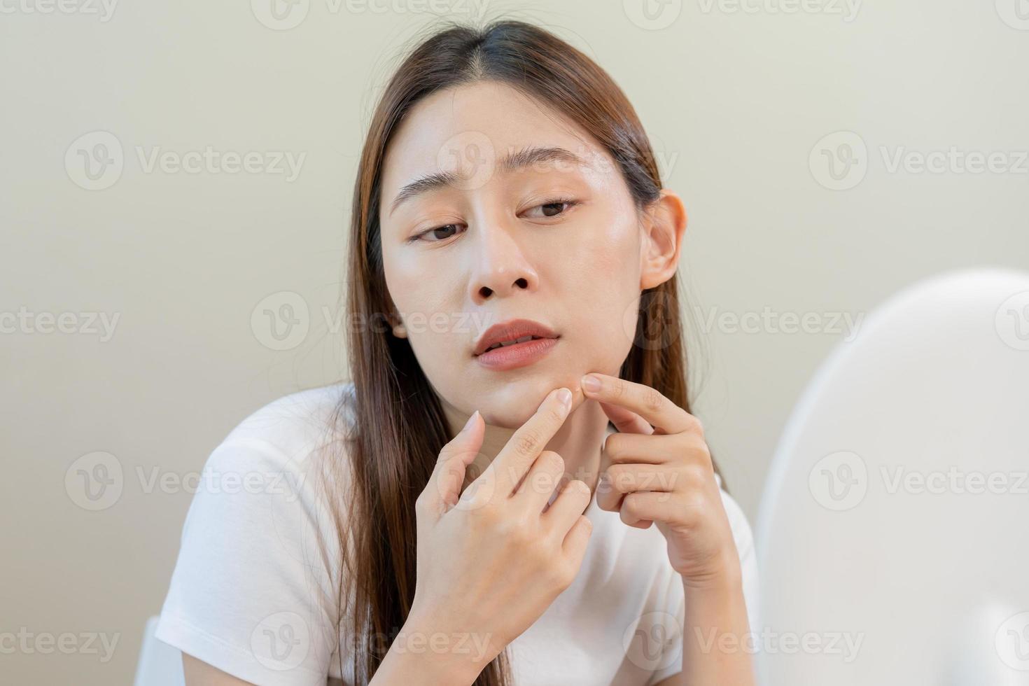 Dermatology, puberty asian young woman, girl looking into mirror, allergy when wear mask and cosmetic, show squeezing pimple spot for removing from face.Beauty care from skin problem by acne treatment photo