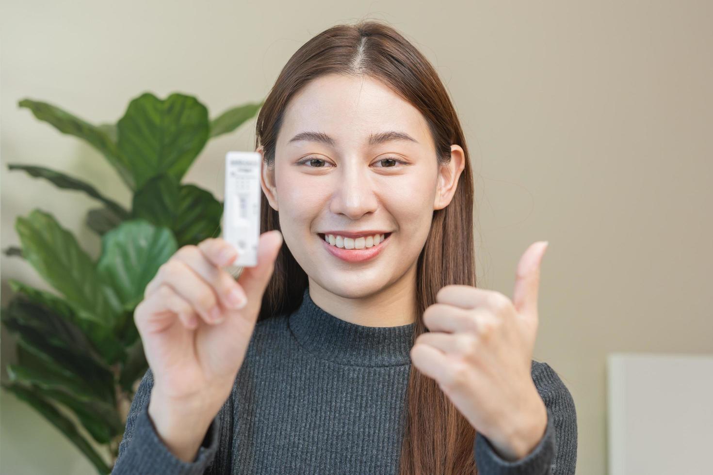 pandemia de enfermedad, sonrisa asiático joven mujer, niña mano espectáculo participación atk, antígeno equipo yo prueba. presentando dispositivo nasal, nariz torunda prueba para posible infección de corona, codicioso a hogar. salud cuidado. foto