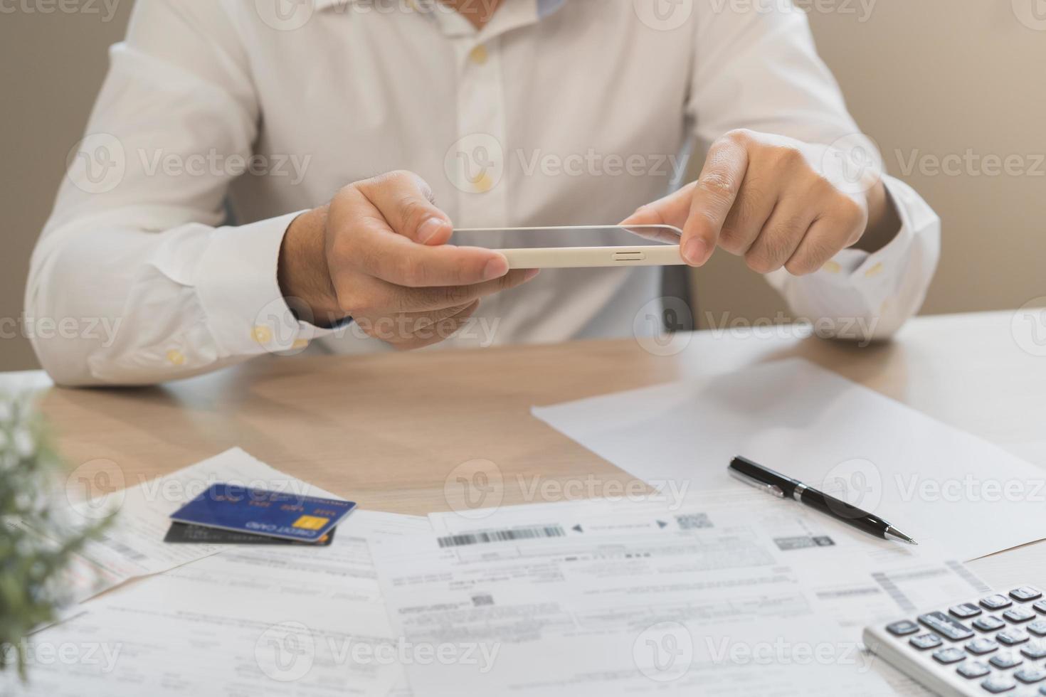Cost, budget asian young man calculate expense, spending and check from invoice, use smartphone, mobile phone pay payment internet online of credit card at home. Technology of finance, financial. photo