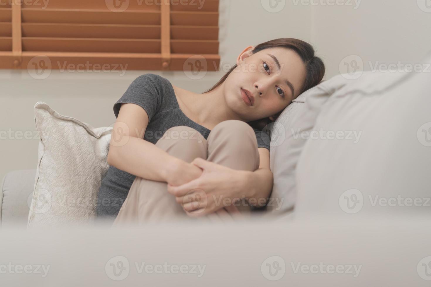 Mental health, depressed sad asian young woman, girl sitting on sofa, couch, expression to face difficulty, failure and exhausted. Thoughtful worried suffering depression feeling lonely, alone at home photo
