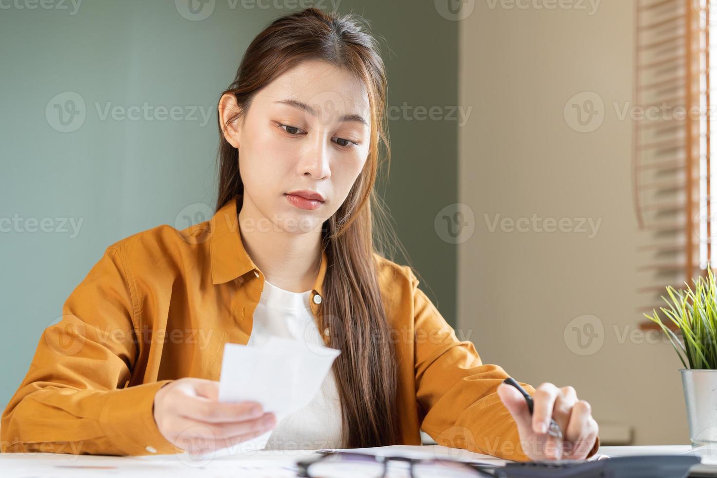 Asian young employee, business woman calculate tax income and expenses, bills, credit card for payment or payday on table at home office. Financial, finance people concept. photo