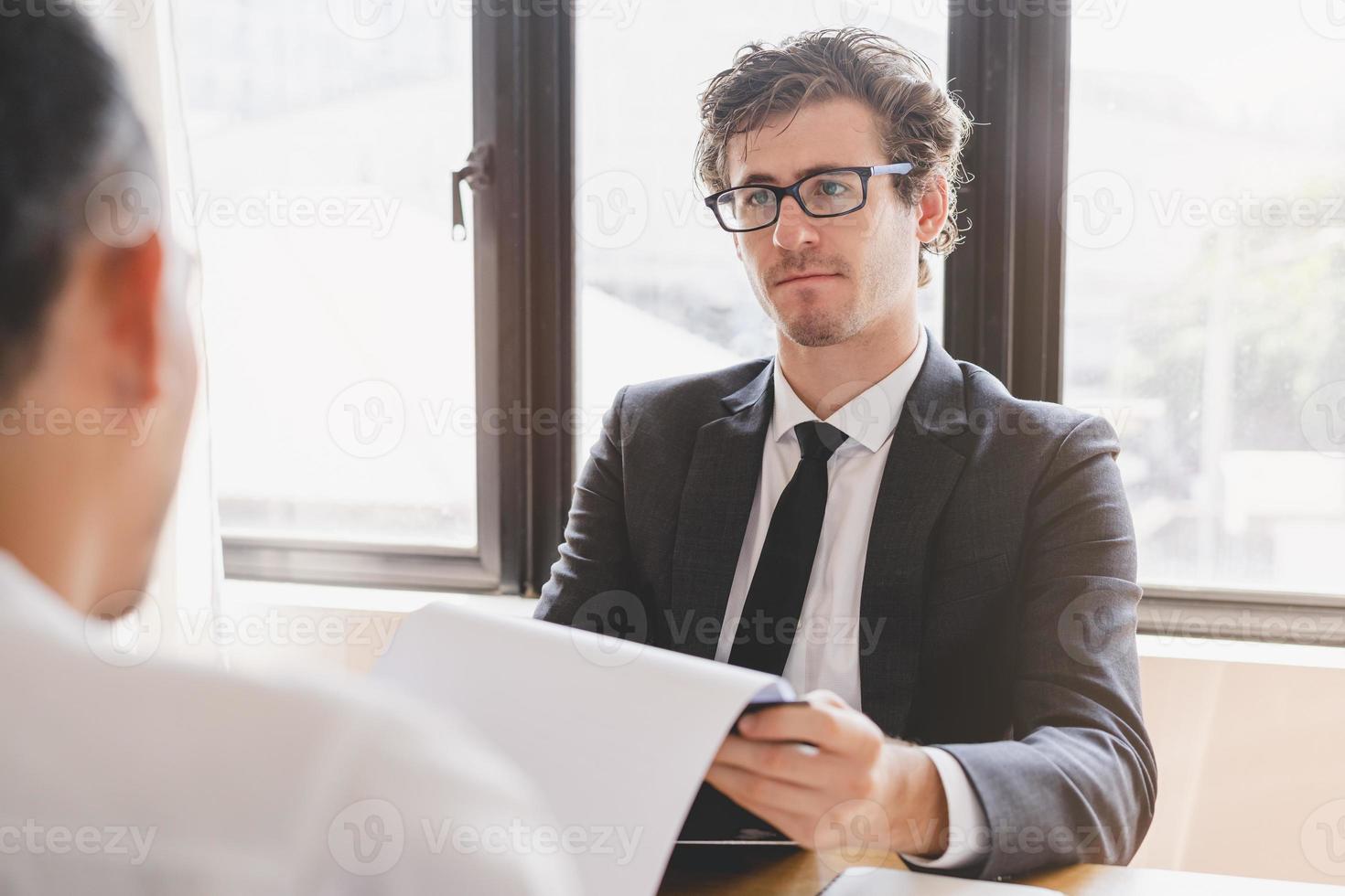 asiático joven gerente, empleador hombre entrevista con persona, tener pregunta acerca de currículum y escucha a candidato respuesta, conversacion juntos a oficina. reclutamiento empleado trabajo concepto. foto