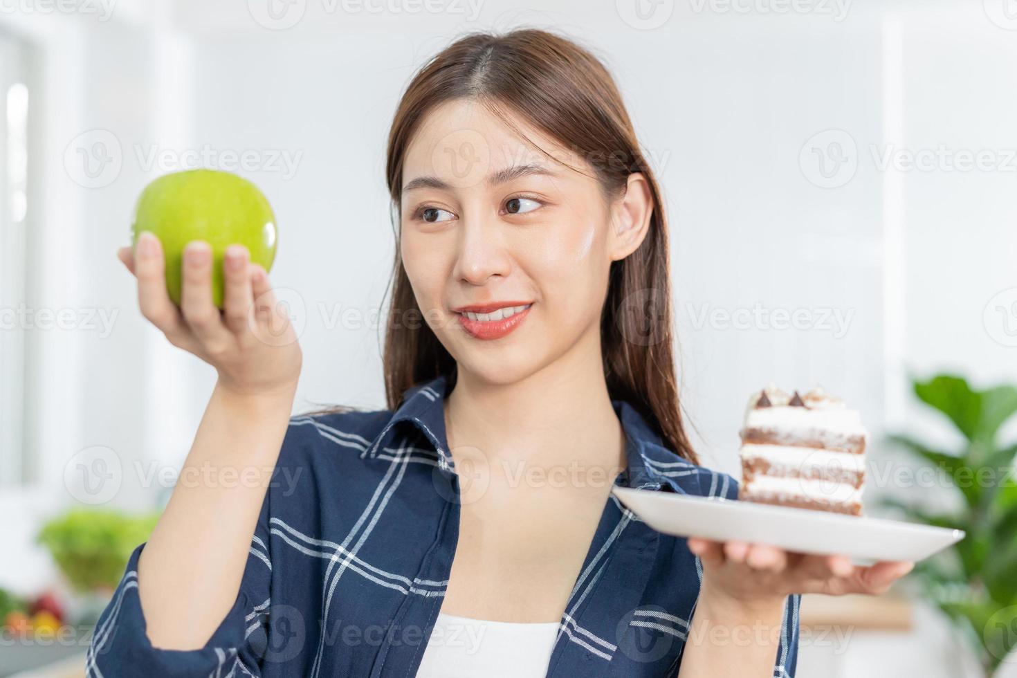 Diet asian young woman lose weight for health choosing to eat green apple, fruit do not choose eat chocolate cake, bakery because will make fat when hungry, female weight loss person, temptation food photo