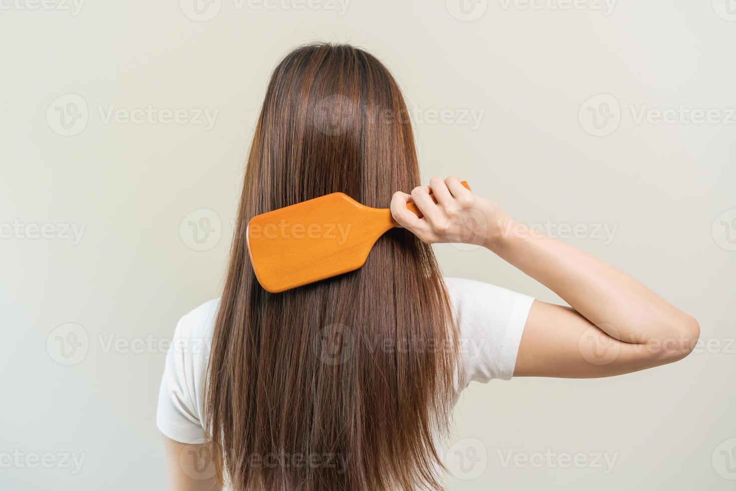 Health hair care, beauty makeup asian woman hand in holding hairbrush and brushing, combing her long straight hair in the morning routine after salon treatment, hairstyle. Isolated on white background photo