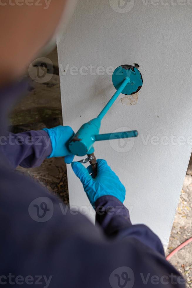 Pest exterminator employees are using pesticide sprayer at client's home and searching for as many nests as possible. An employee from pest control company is spraying chemicals to kill the insects. photo