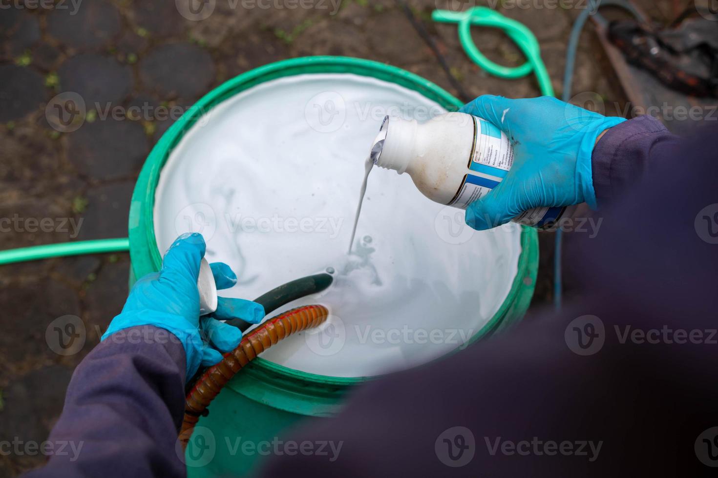 Pest exterminator employees are using pesticide sprayer at client's home and searching for as many nests as possible. An employee from pest control company is spraying chemicals to kill the insects. photo