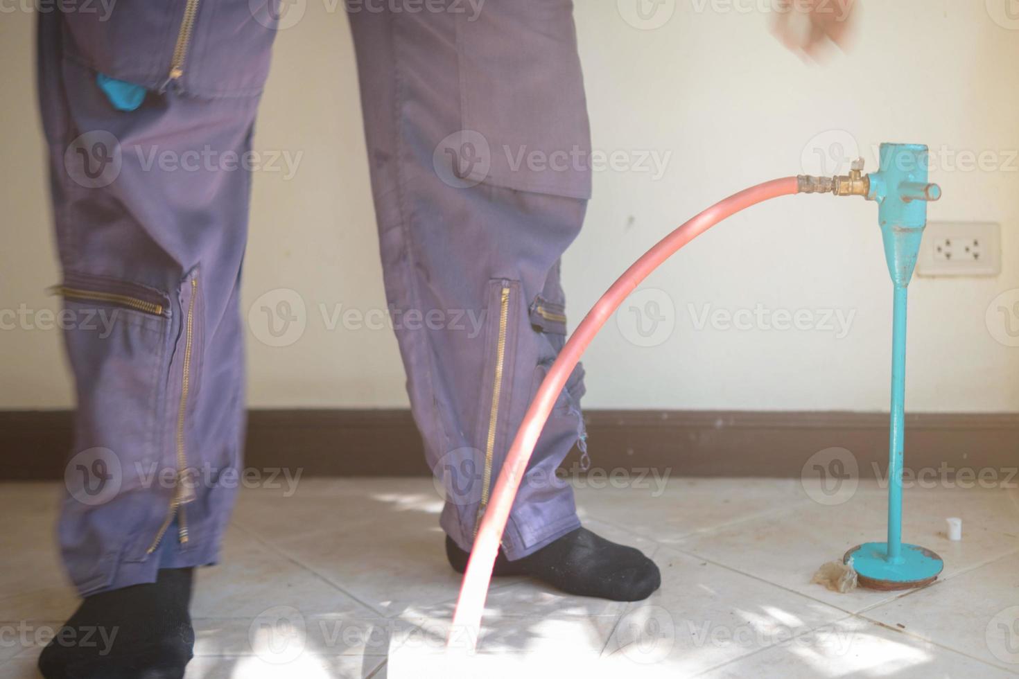 exterminate termite control company employee is using a termite sprayer at customer's house and searching for termite nests to eliminate. exterminate control worker spraying chemical insect repellant photo