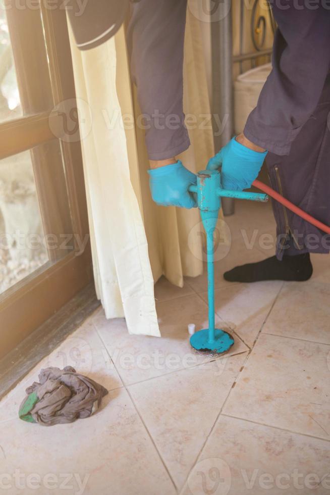 Pest exterminator employees are using pesticide sprayer at client's home and searching for as many nests as possible. An employee from pest control company is spraying chemicals to kill the insects. photo