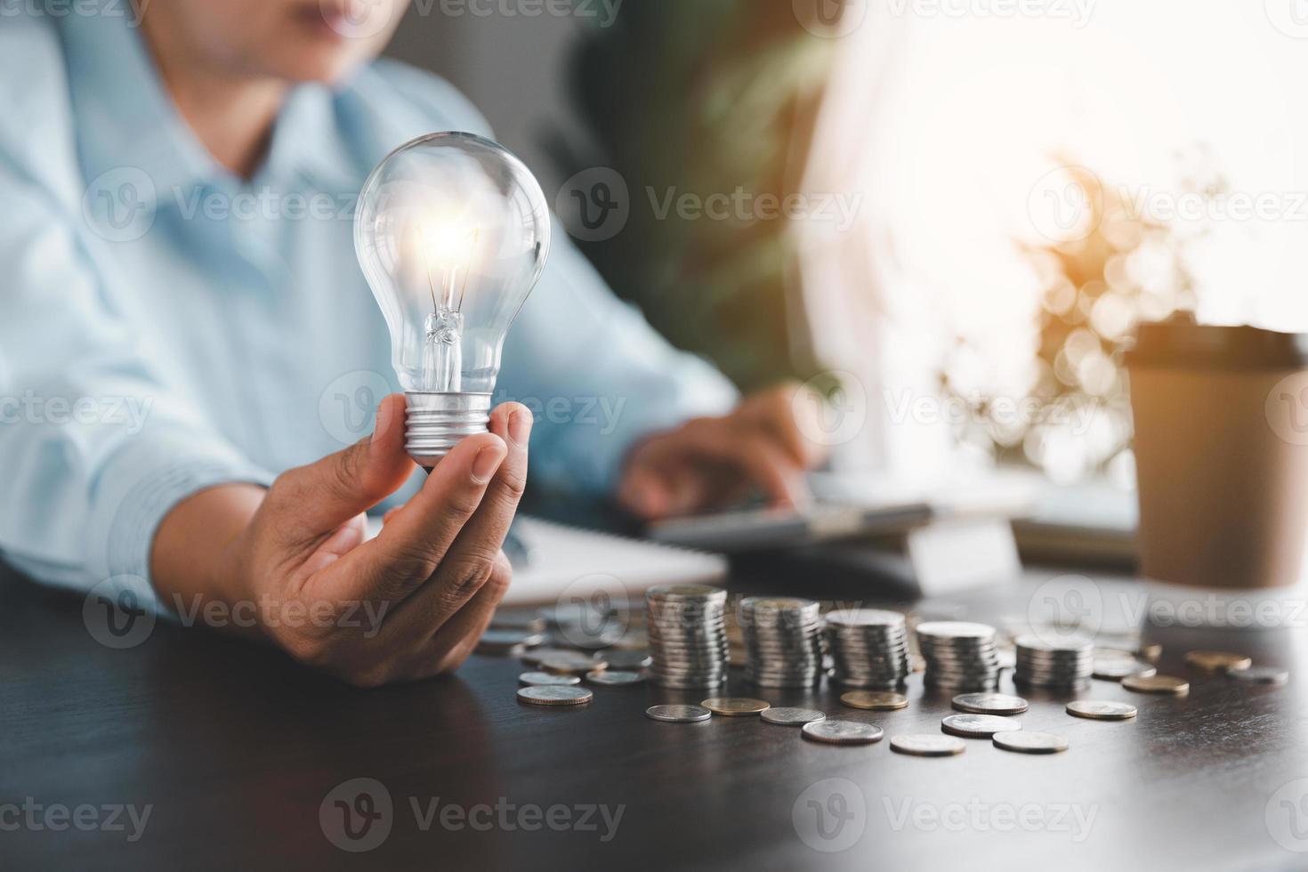 Businesswoman hand holding lightbulb with cost calculator. Idea of saving energy and accounting finance in home and family, save world and energy power. Save energy plan concept. photo
