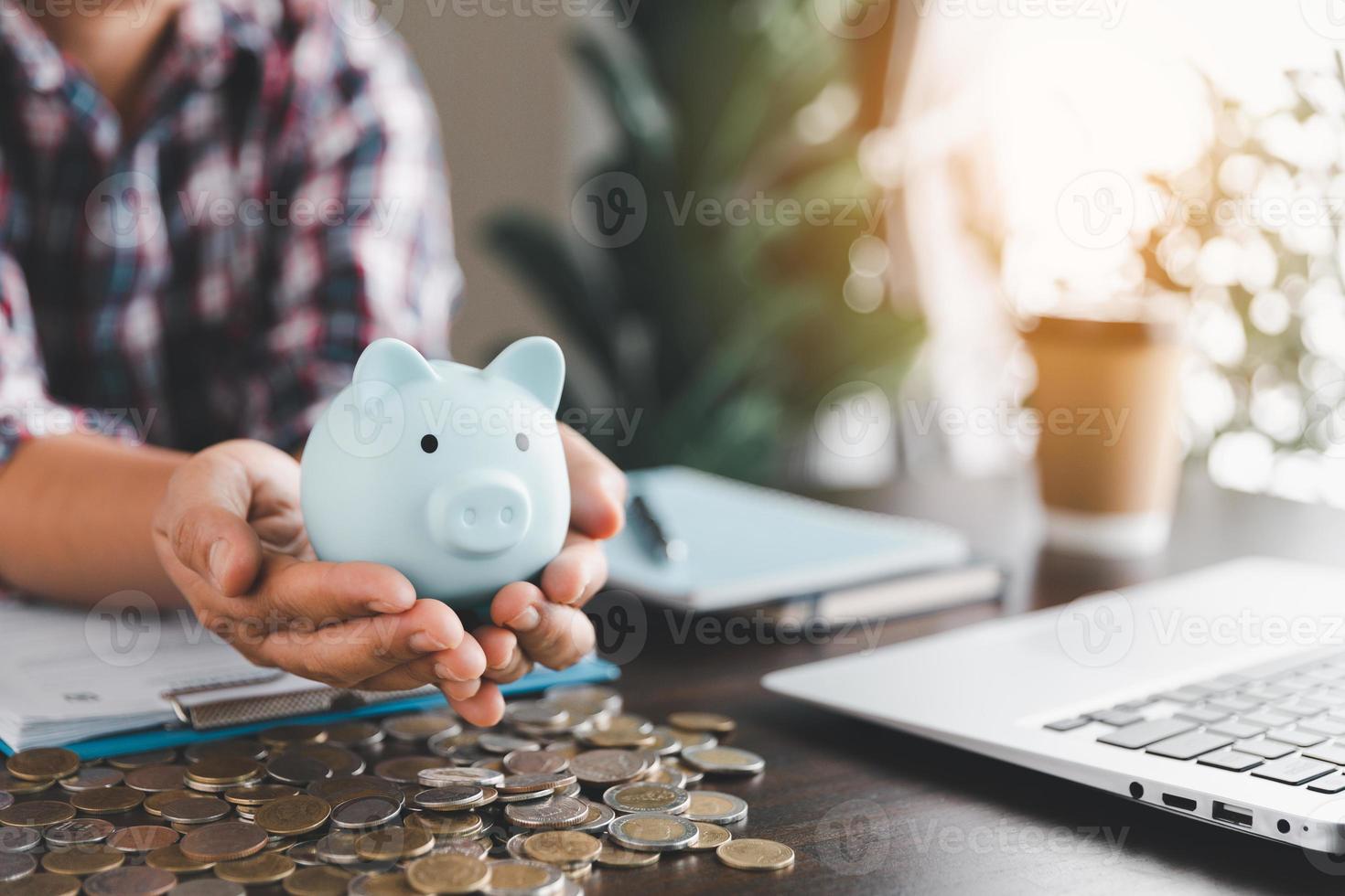 mujer de negocios mano participación azul cerdito banco en madera mesa fondo, ahorro dinero riqueza y financiero concepto, finanzas, inversión, financiero planificación. financiero planificación depositar para Jubilación. foto