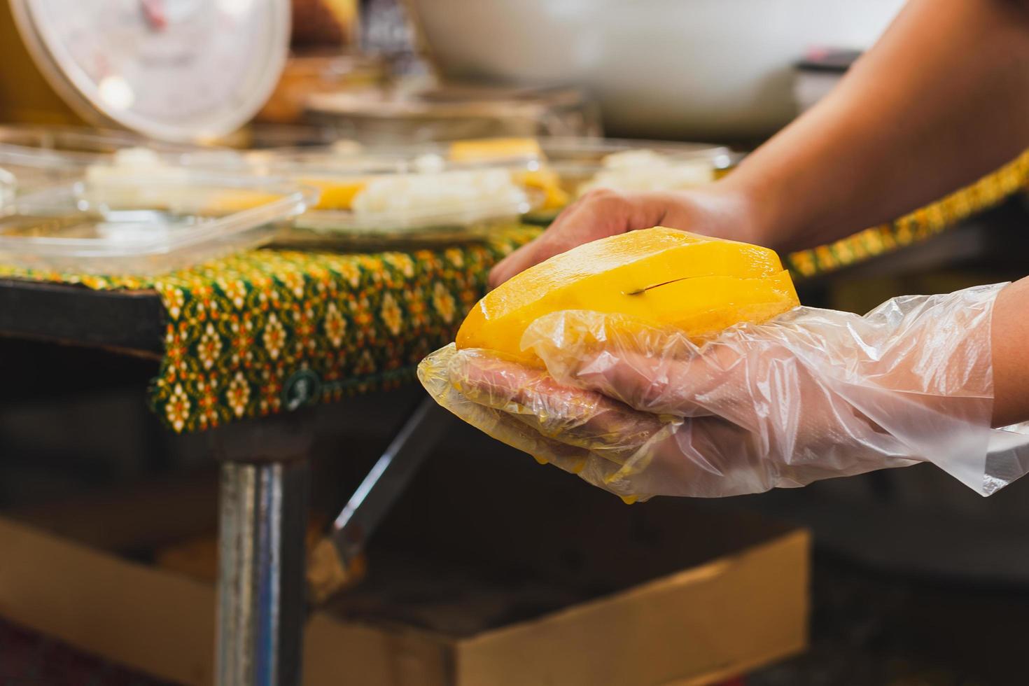 Woman hand peeling ripe yellow mango in local store. photo