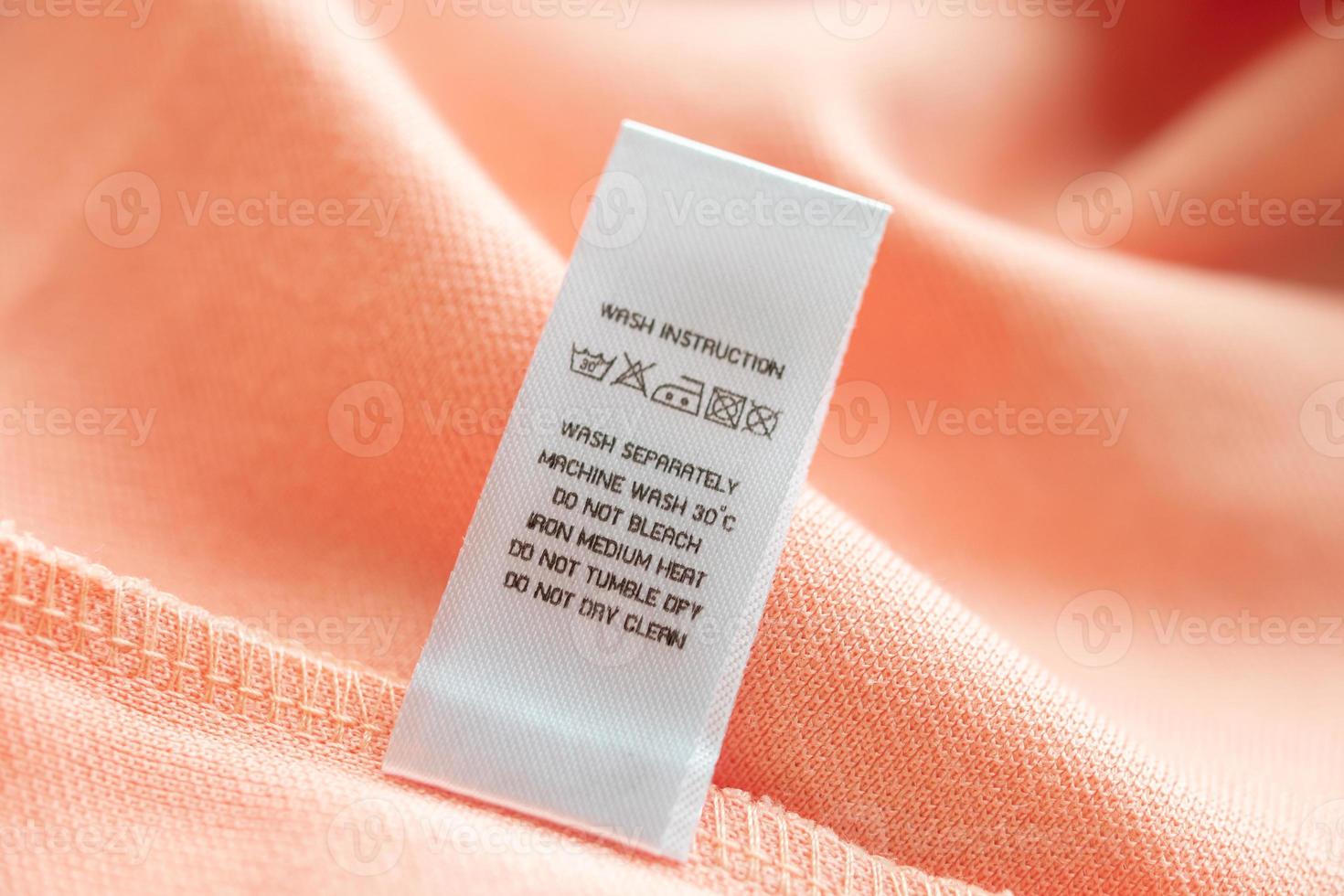 White laundry care washing instructions clothes label on pink cotton shirt photo