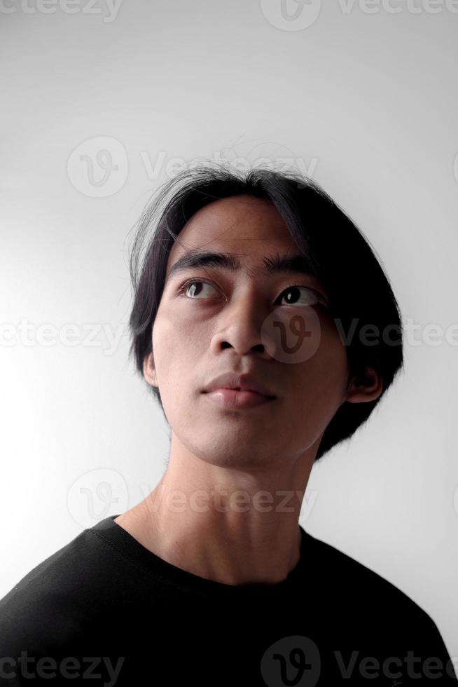 Dramatic low light portrait of handsome Asian man looking up. Side light effect photo