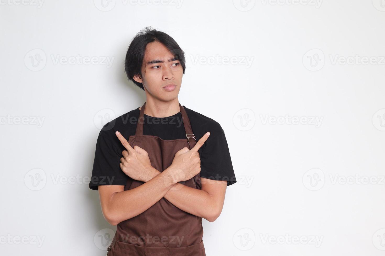 Portrait of attractive Asian barista man in brown apron showing product, pointing up right and left, showing two option of choices. Advertising concept. Isolated image on white background photo