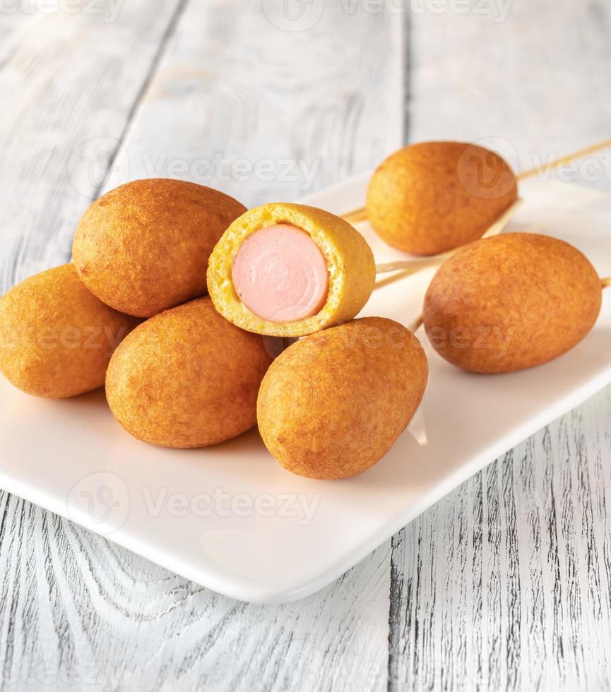 Corn dogs on white serving plate photo