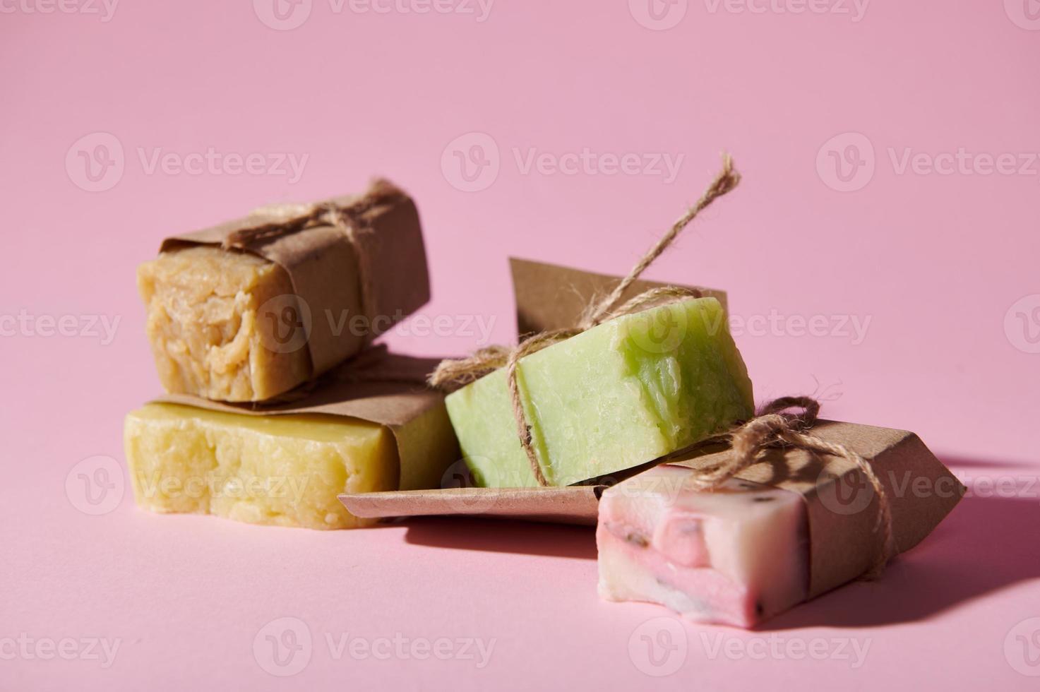 Assortment of multi-colored cold-pressed organic soaps with natural herbal and floral ingredients, isolated on pink photo