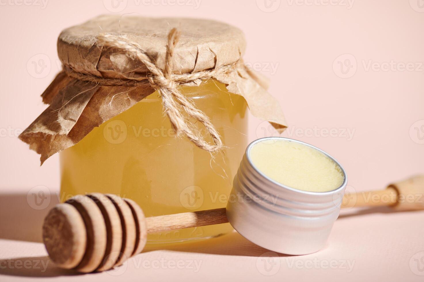 Selective focus on a jar with wax and a can with organic honey against beige pastel background. Honey spa and body care photo