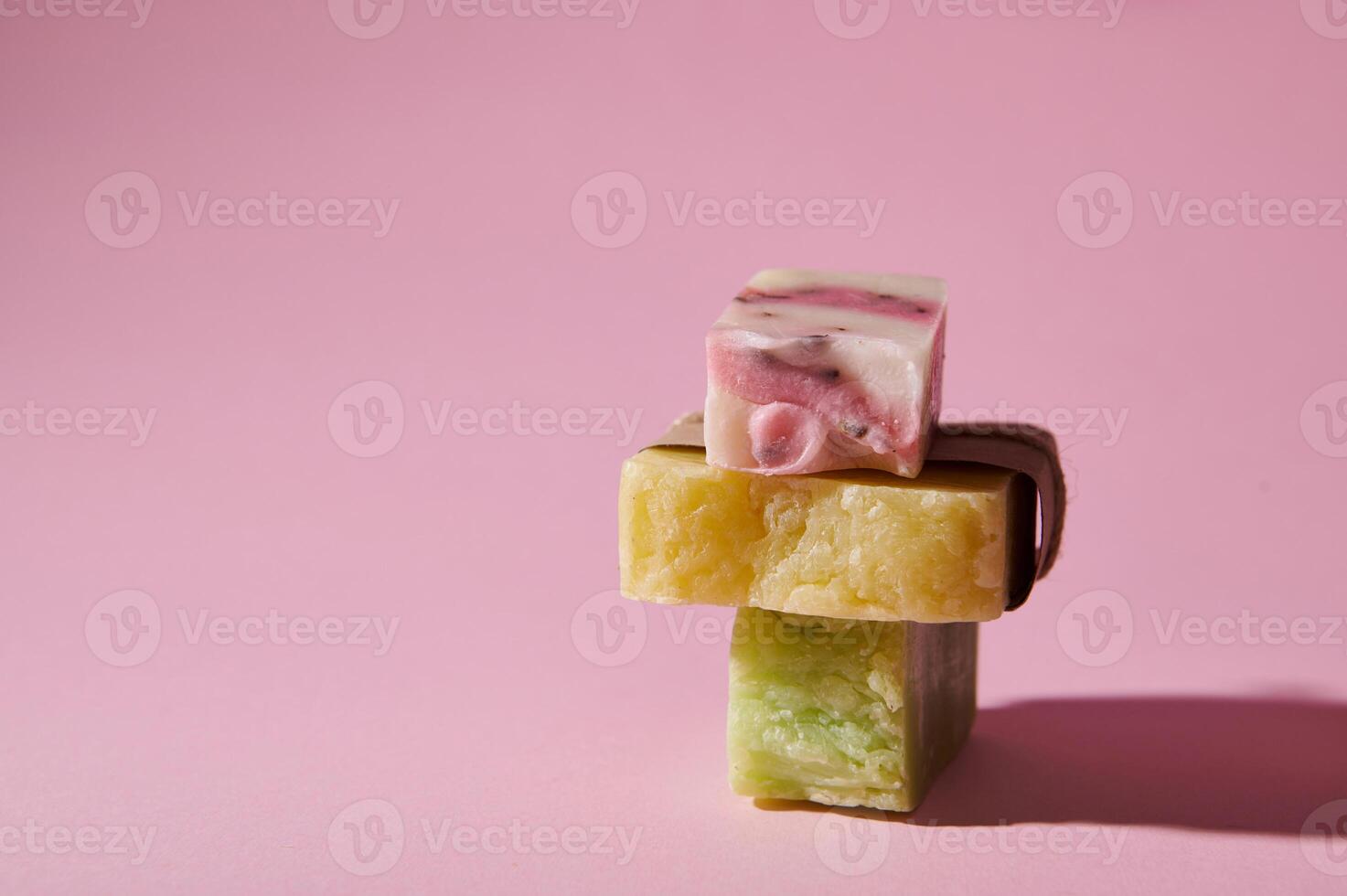 Stack of homemade natural eco soap bars with organic herbal ingredients for health and spa, isolated on pink background photo