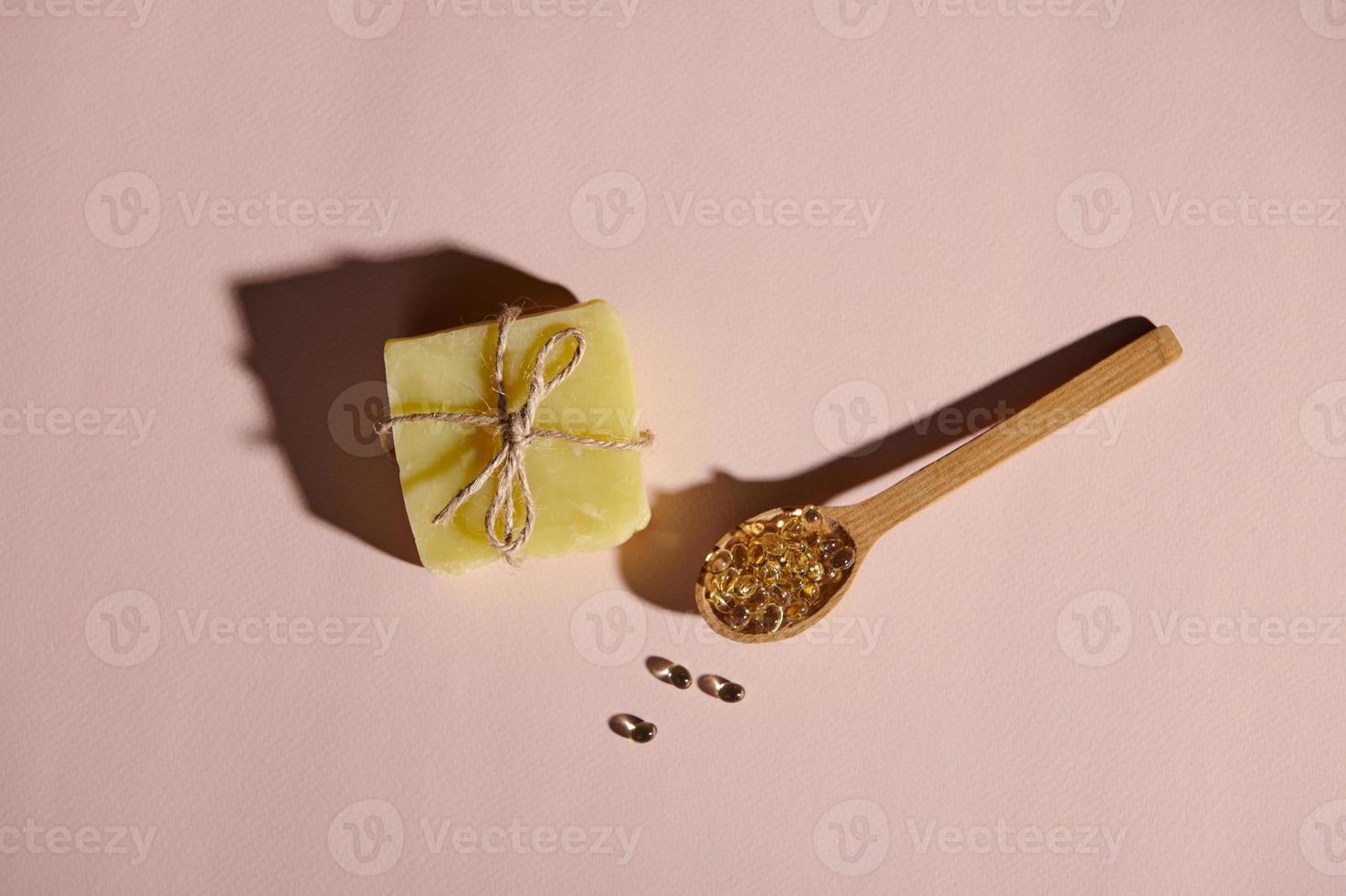 ver desde encima de gelatina cápsulas en de madera cuchara y jabón bar atado con lino cuerda en aislado rosado pastel antecedentes foto