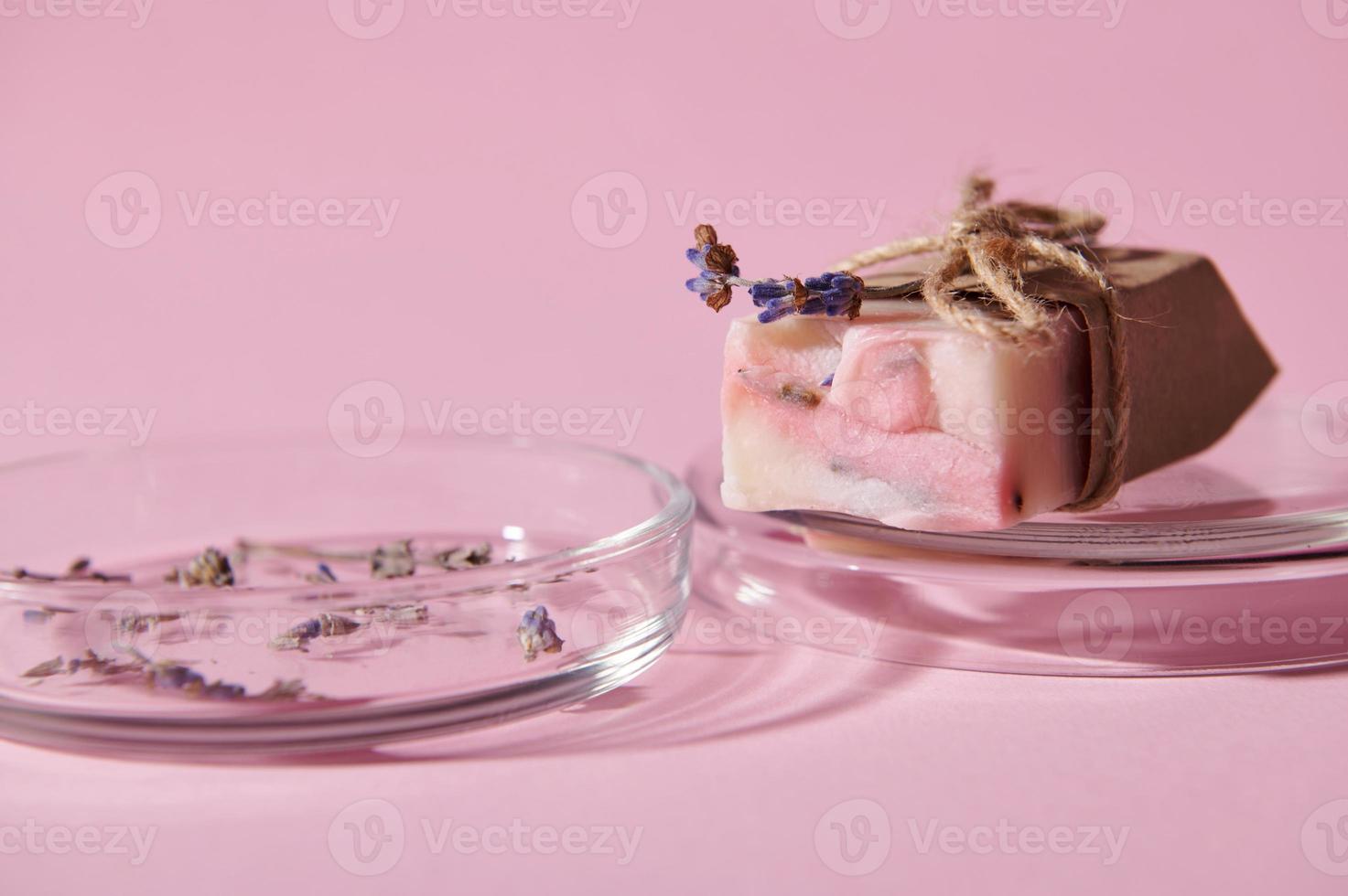 Focus on a bar of pink soap with natural ingredients, on petri dish, isolated over pink background. Hygiene. Purity photo