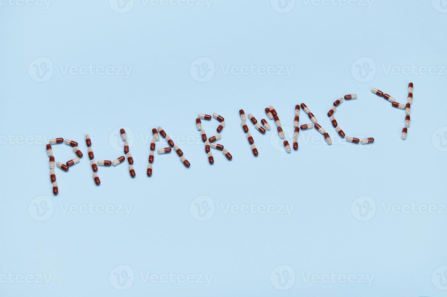 The word PHARMACY laid out with medical capsule on blue background. Copy space. World Pharmacist Day. Top view photo
