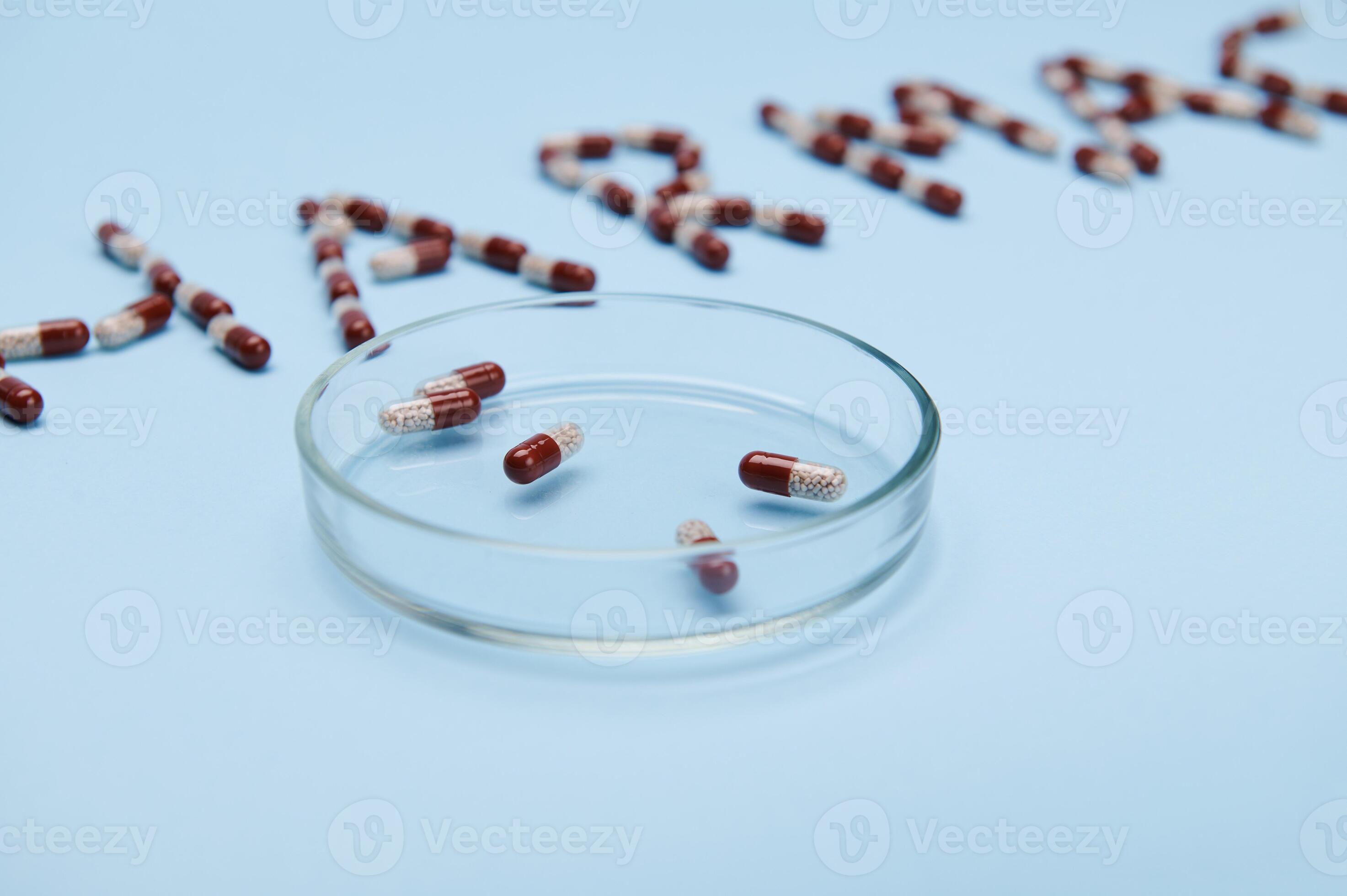 A petri dish with medical gelatin capsules on isolated blue background