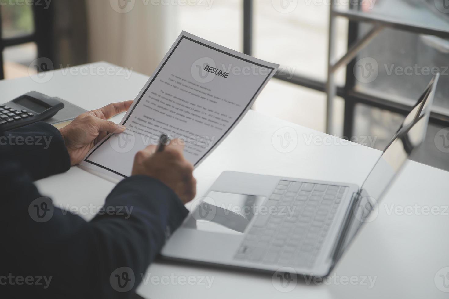 Businessman or job seeker review his resume on his desk before send to finding a new job with pen, necktie, glasses and digital tablet. photo