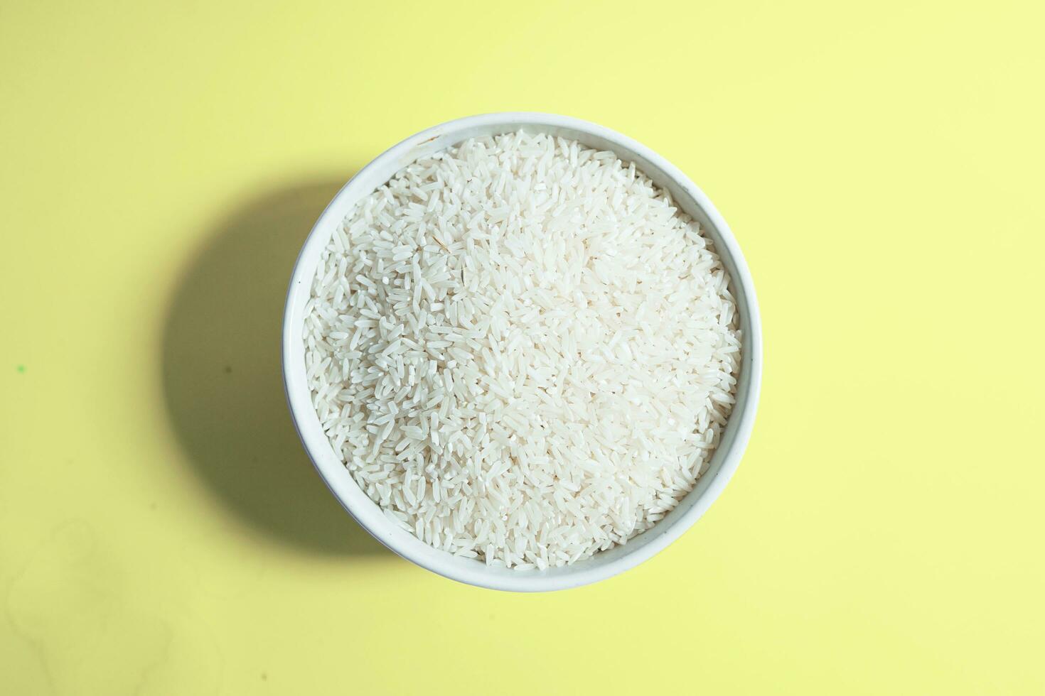 Healthy food. White ceramic bowl with high carb rice on yellow background. Top view, high resolution product. photo