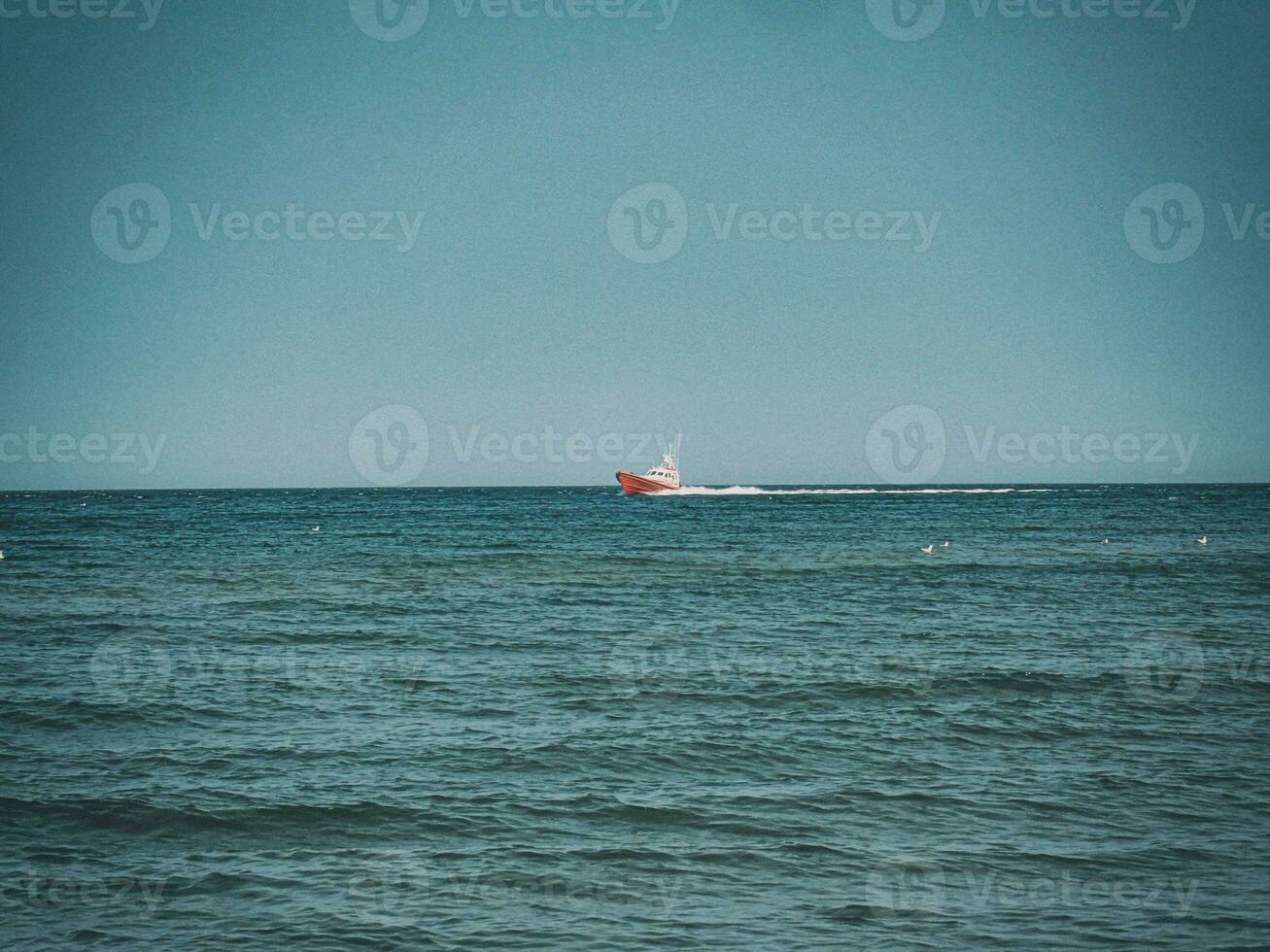 white and red sea rescue vessel sailing on the Polish Baltic Sea against the blue sky on a warm summer day photo