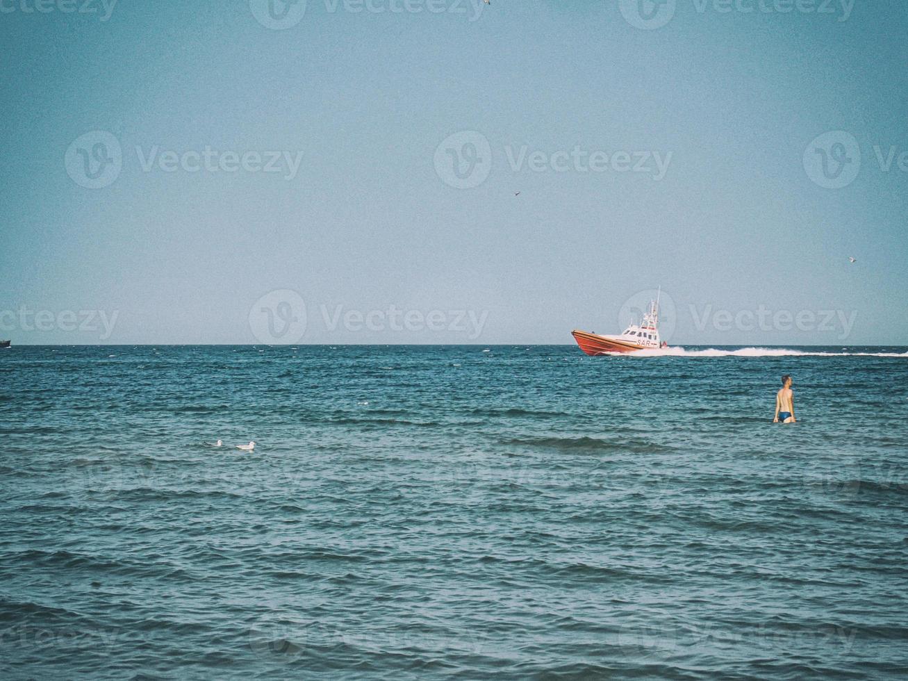 white and red sea rescue vessel sailing on the Polish Baltic Sea against the blue sky on a warm summer day photo