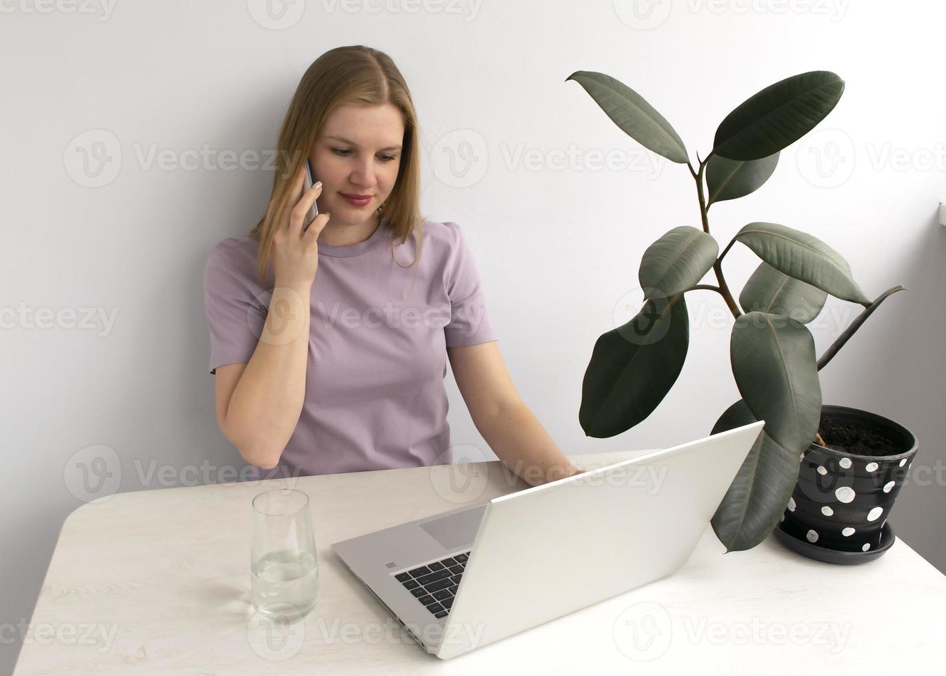 beautiful caucasian woman working with laptop while drinking glass of water on a table at home. photo