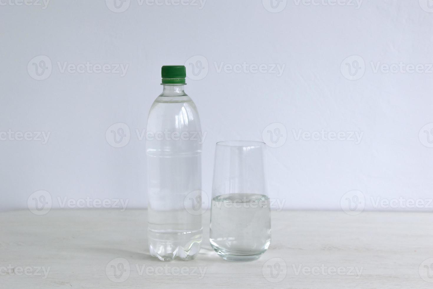 Bottle and glass with water on background photo