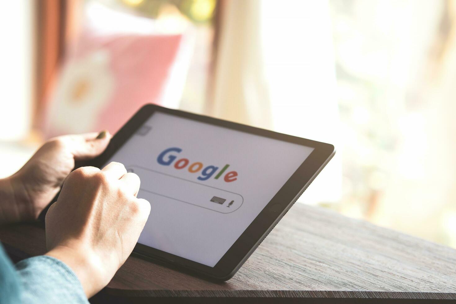 April 14, 2023 in Bangkok, Thailand. A woman holds iPad to search on Google website at Caf shop on holiday for news update source of information, entertainment media, news and articles photo